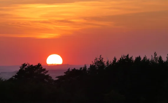 eine Sonne am Horizont die den Himmel orangerot färbt